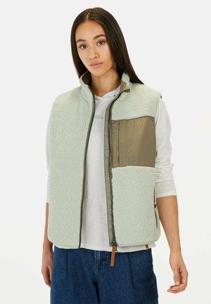 Fleece vest in light mint green with a zippered front, high collar, and a contrast olive green pocket. Features textured fabric and side pockets.