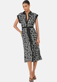 Rochie midi alb-negru cu buline, cu mâneci scurte, deschidere cu nasturi în față și curea cu legare proprie la talie. Material moale, fluid.