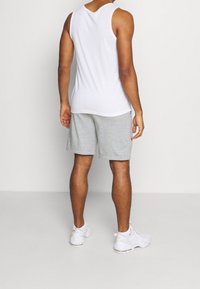 Herrsportklädsel som består av en enkel vit linne, grå shorts och vita sneakers. Linnen har en rund halsringning och är ärmlöst.