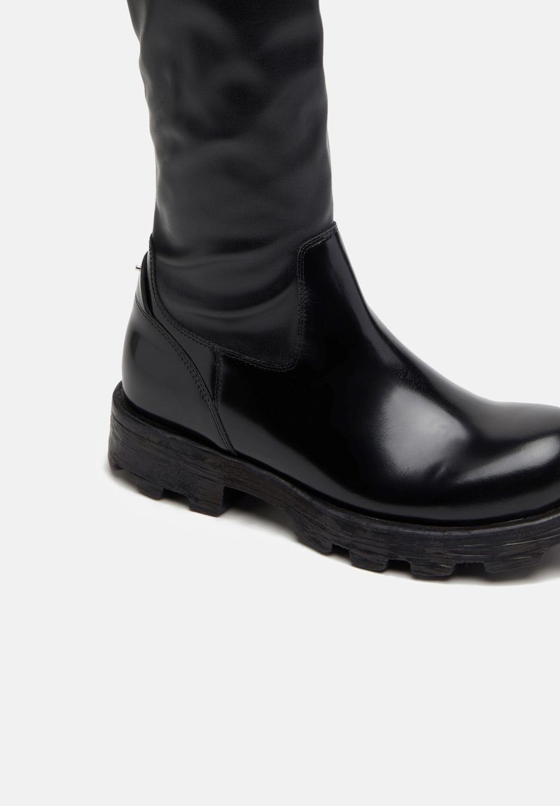Bota alta de cuero negro hasta la rodilla con acabado suave, caña texturizada, suela negra de goma gruesa y diseño limpio y minimalista.