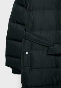 Giacca a vento nera con design trapuntato, dotata di una cintura e di dettagli in metallo sui lati. Texture liscia e lucida.