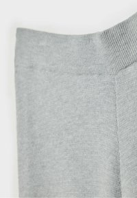 Gros plan sur un tissu en maille grise montrant une ceinture côtelée et une texture lisse sur un pantalon ou des leggings doux.