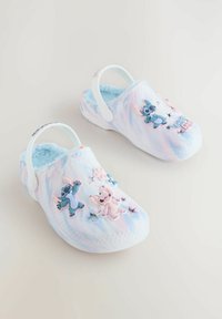 Zuecos en tonos azul claro y rosa con un diseño tie-dye, forrados con un material suave y con acentos de personajes en 3D de plástico y cortes en forma de estrella en la parte superior.
