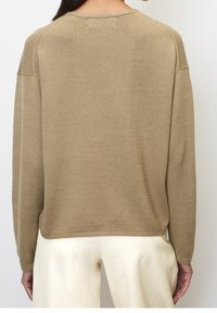 Maglione beige a maglia con una vestibilità rilassata, collo rotondo e spalle scese. Tessuto testurizzato, rifinito con orlo a coste. Chiunque indossi pantaloni chiari.