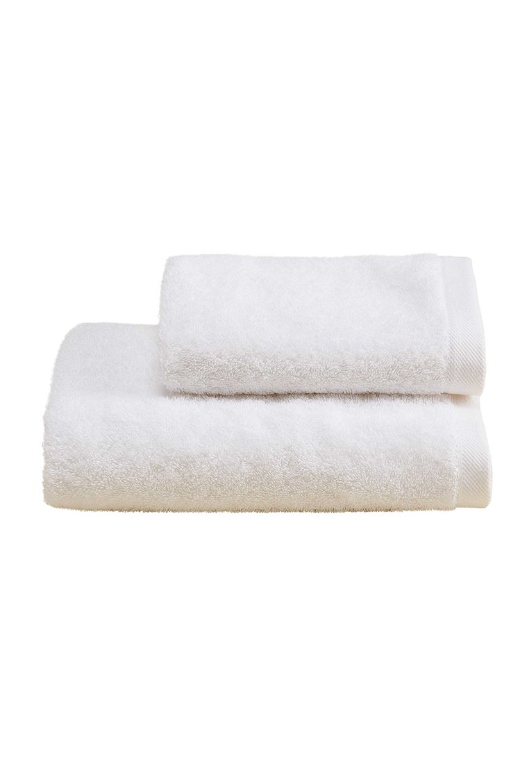 Due asciugamani bianchi impilati, realizzati in morbido cotone. L'asciugamano più grande è in basso, con una superficie morbida e testurizzata e un bordo intrecciato.