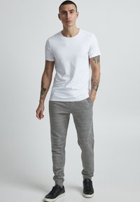White short-sleeve t-shirt paired with gray heather joggers, featuring a relaxed fit and side pockets, complemented by black sneakers.