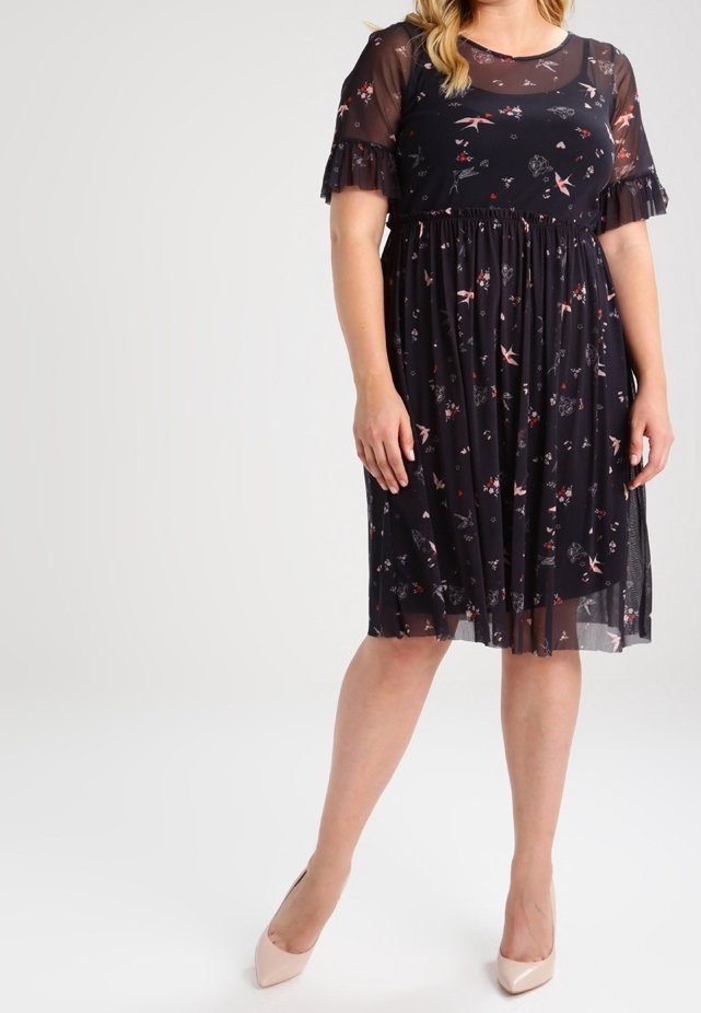 Svart blommig klänning med genomskinliga ärmar, korta volanger i ärmsluten och sammanknuten midja. Har rosa och vita blommönster på en mörk bakgrund.