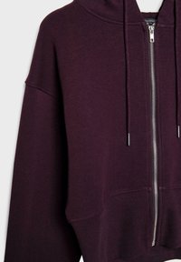 Felpa con zip viola caratterizzata da un cappuccio aderente, polsini a coste e una forma squadrata. Realizzata in un tessuto morbido con una texture liscia.