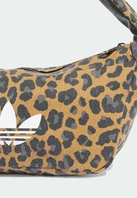 Leopardskrift veske i beige og grått stoff med en buet form, utstyrt med en hvit Adidas-logo og en glidelås på toppen.