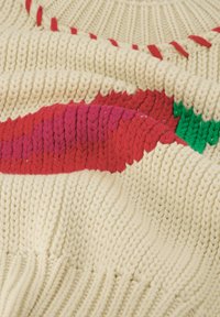 Gebreid sweater in crème met levendige rode en roze bladvormen. Heeft een gestructureerde brei en een gladde afwerking. Accenten zijn onder andere groene details.