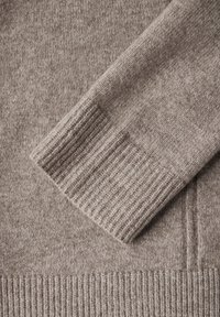 Braun gestrickter Pulloverstoff mit einem Rippbündchen-Detail, das über eine weiche Textur und ein dezentes Sprenkelmuster verfügt. Die Form ist lässig mit einem sauberen Finish.