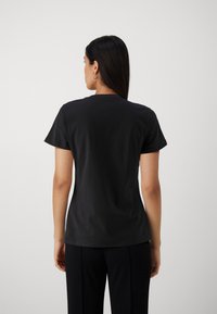 T-shirt in cotone nero con scollatura rotonda classica e maniche corte. Texture liscia, design aderente e senza motivi visibili o loghi.