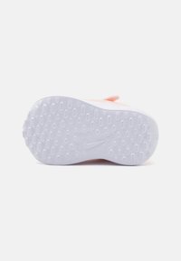 Semelle de chaussure Nike en caoutchouc blanc, présentant une surface texturée avec des motifs circulaires et un logo estampé près du talon.