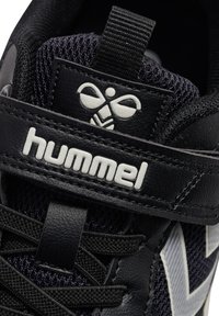 Schwarzer Sportschuh aus Mesh- und Leder-Materialien, mit weißem Logo, schwarzen Schnürsenkeln und strukturiertem Design an den Seiten.