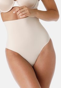 Slip modellante beige a vita alta realizzato in tessuto liscio e elastico, caratterizzato da linee pulite e un design minimal per un aspetto senza soluzione di continuità.