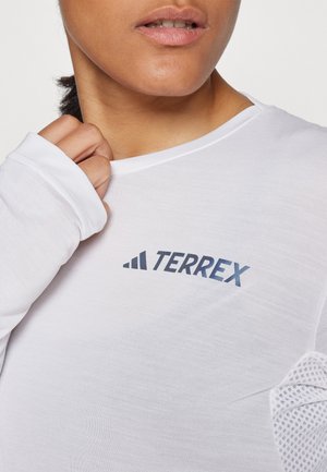 White long-sleeve shirt featuring a blue "TERREX" logo. The fabric is lightweight with textured mesh accents on the shoulders.