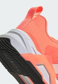 Coral athletic shoe with a textured upper, rubber sole, and white accents; features a pull tab labeled "TRAINING" on the heel.