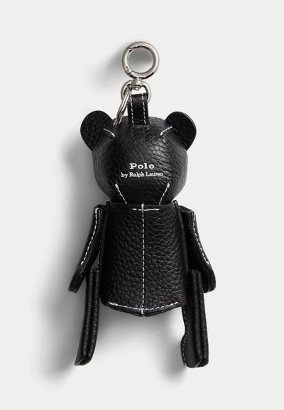 Μπρελόκ αρκούδας από μαύρο δερμάτινο με υφή, με λευκή ραφή και ασημένιο κούμπωμα, με την επιγραφή "Polo by Ralph Lauren" στο κεφάλι.