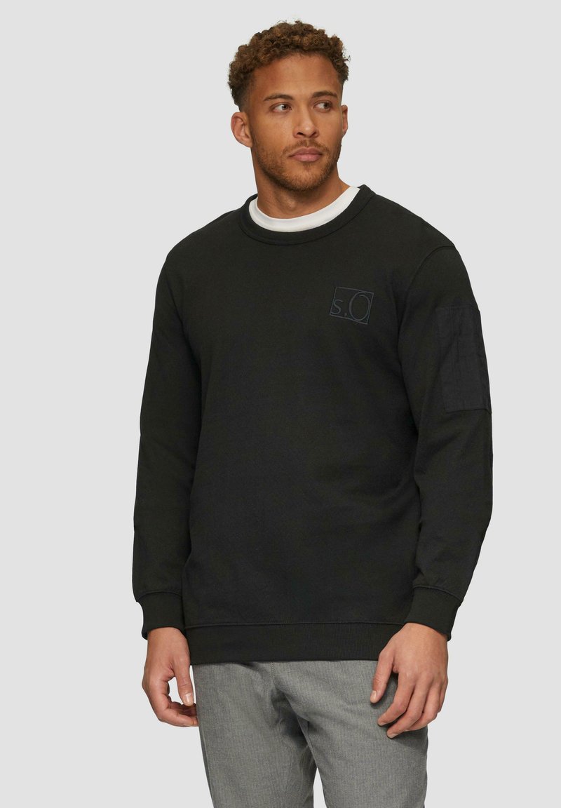 Zwarte sweatshirt met een ronde hals, lange mouwen en een rechthoekig logo op de borst. Beschikt over een textuurstof en geribbelde manchetten.