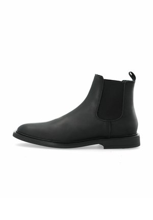 Botín Chelsea de cuero negro con paneles laterales elásticos, puntera redondeada y suela plana. Diseño minimalista con una lengüeta en la parte trasera.