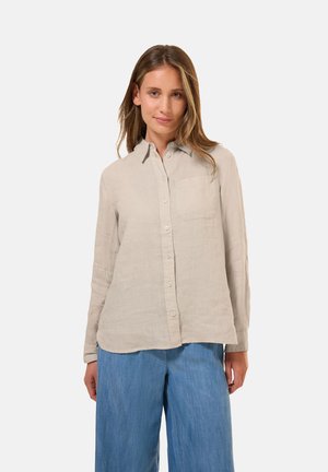 Camicia beige chiaro a maniche lunghe con colletto, bottoni frontali e una tasca sul petto. Tessuto di lino con una superficie leggermente strutturata.