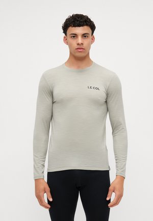 Lys grå langærmet atletisk skjorte med rund hals, prydet med en subtil tekstur og sort "LE COL" logo på brystet. Fremstillet af åndbart stof.