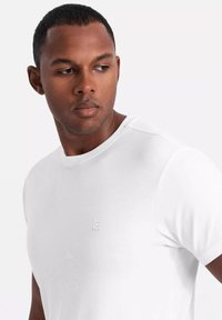 Biała koszulka z okrągłym dekoltem, wykonana z miękkiej bawełny, z delikatnym detalem logo na lewej piersi oraz klasycznym krojem.
