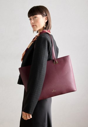 Maroon leather tote bag with a textured finish and gold hardware accents. The bag features sturdy handles and a spacious design.
