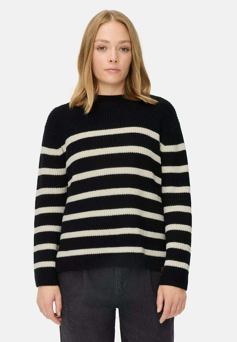 Zwart en crèmekleurig gestreepte trui met geribbelde textuur, ronde hals en brede mouwen. Gecombineerd met donkergrijze broek; minimalistisch ontwerp.