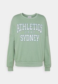 Felpa verde con maniche lunghe, scollo rotondo e design a spalle scese. Presenta testo bianco "ATHLETICS SYDNEY 1987" sul davanti.