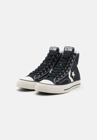 Svarta högskurna sneakers i kanvas med vit gummikappa och sula. Har vit söm och ikonsisk stjärnlogotyp på sidan.