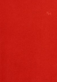 Tissu tricoté rouge, texture lisse, poids moyen, avec des coutures subtiles et un petit logo dans le coin supérieur.