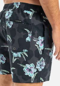 Čierne plavky s kamuflážným vzorom a veľkými svetlomodrými a ružovými kvetmi. Elastický pás s zadnou vreckom a logom značky.