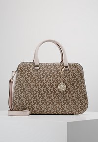 Sac à main DKNY marron et beige à motifs, avec deux poignées, une bandoulière détachable et un pendentif circulaire avec le logo Donna Karan à l'avant.
