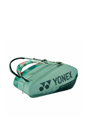 Groene Yonex sporttas met twee met ritsen afgesloten compartimenten en dubbele draagriemen, ontworpen voor het opbergen van rackets en gemakkelijk transport.