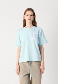 Lichtblauwe katoenen T-shirt met korte mouwen, ronde hals en een klein wit en paars "Calvin Klein" logo op de borst.