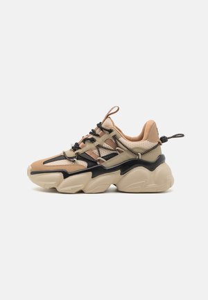 Beige en zwarte sneaker met een stevige zool, bovenwerk van mesh, textuuraccenten en contrasterende veters. Voorzien van een trekband aan de achterkant.