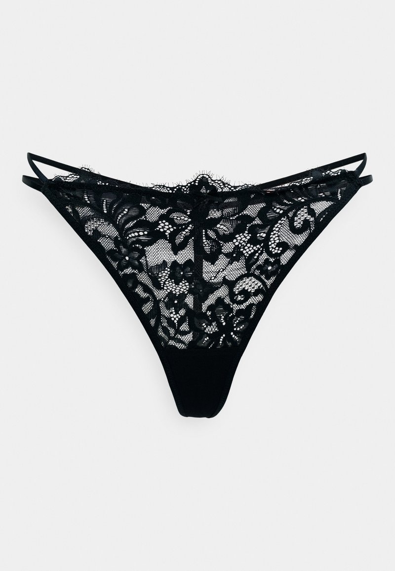 String en dentelle noire avec motif floral, présentant une devant en transparence, un dos uni et des bretelles fines et ajustables. Texture lisse avec des détails élaborés.