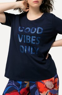 Camiseta de algodón azul marino con el texto "SOLO BUENAS VIBRACIONES" en letras azules a rayas. Manga corta y un corte relajado.