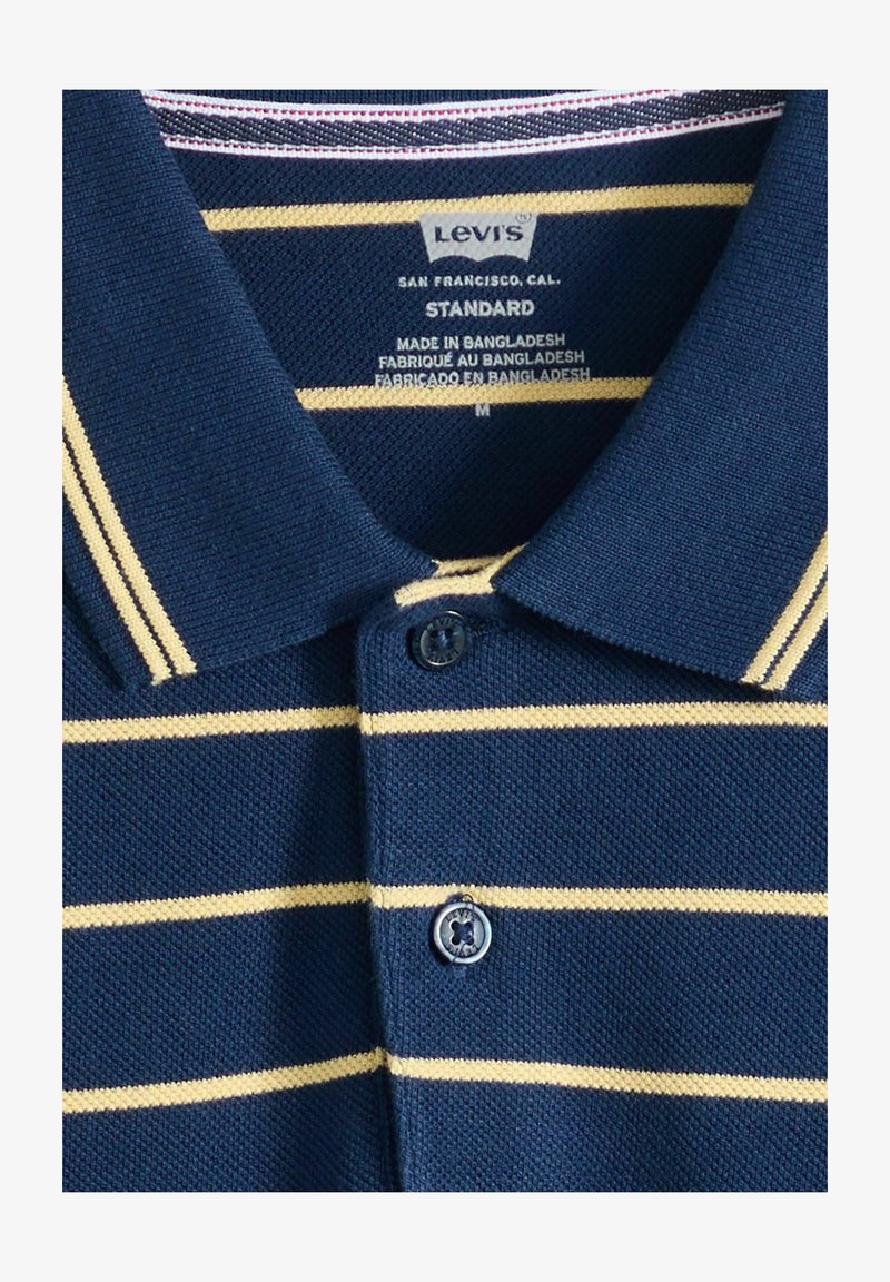 Marineblå Levi's polo med beige horisontale striber, knappet krave, størrelse medium, lavet i Bangladesh.