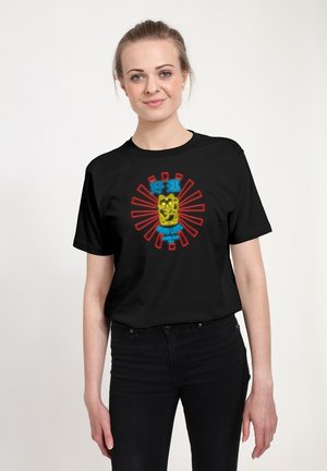 Kvinde iført en sort t-shirt med en neon-stil lykkekat, røde stråler, og tekst der står "Good Luck" og "Ramen Bar Tokyo."