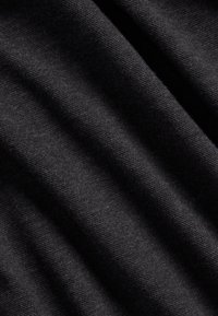 Svart tyg med en mjuk, texturerad yta som har ett diagonalt ribbmönster, med mjuka veck och skuggor.