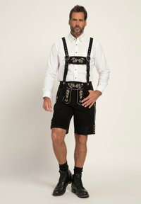 Black suede lederhosen with silver embroidery, adjustable suspender straps, side buttons, and paired with a white collared shirt and black boots.