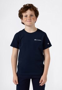 Camiseta de algodón de manga corta en azul marino con un logo en blanco de "Champion" en el pecho y un pequeño logo en la manga.