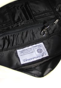 Schwarzes Innenfutter einer Tasche aus glattem, strukturiertem Stoff. Verfügt über Fächer, einen Reißverschluss und ein Etikett mit Logo der Marke. Gepolstertes Design für Schutz.