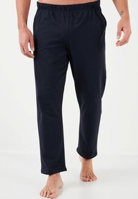 Pantalones de cintura elástica en azul marino, hechos de una tela suave. Presentan bolsillos laterales y un ajuste holgado con un diseño de pierna recta.