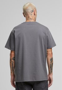 T-shirt en coton gris avec un col rond et des manches courtes, dotée d'une coupe décontractée et d'une texture lisse. Pas de motifs ni de logos visibles.