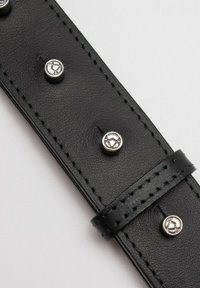 Cinturino in pelle nera con rivetti argentati, bordi cuciti, una superficie liscia e una fascia centrale per il fissaggio.