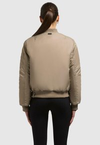 Khaki Bomberjacke mit gerippten Bündchen und Saum, ausgestattet mit einer glatten Textur, seitlichen Taschen und Nähdetails für zusätzliche Struktur.