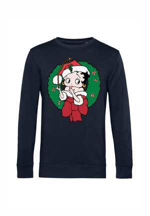 Marineblå sweatshirt med en tegneseriefigur i julesweater, omgivet af en grøn krans med røde accenter og en sløjfe.